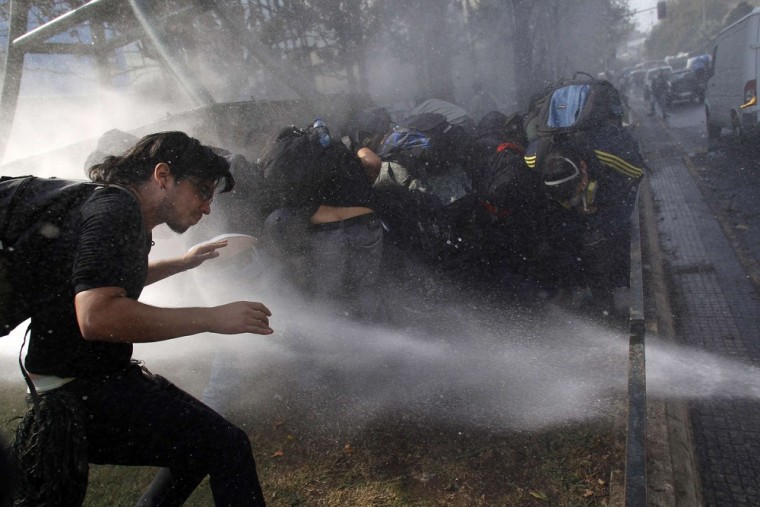 Student protesters take cover from jets of water spray during a demonstration against the government in Santiago, Chile on April 25. Chilean students have been protesting against what they say is profiteering in the state education system and are demanding changes.