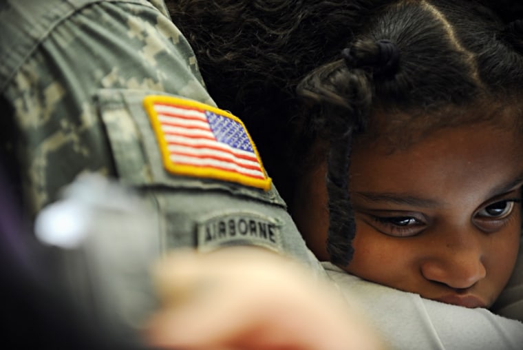 Breanna Summers, 8, rests in the arms of her father, Army helicopter mechanic Damion Summers, during a program to honor military families at Lee Hall Elementary school in Newport News, Va. on April 25.
