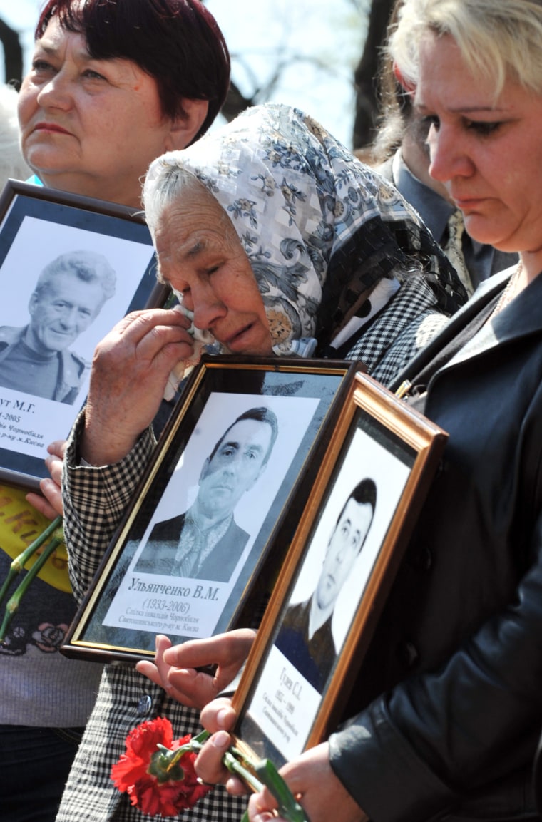 Victims of Chernobyl nuclear accident's widows hold pictures of their late husbands during a memorial ceremony at the Chernobyl victims memorial in Kiev on April 26.