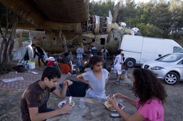 An Israeli family enjoys their Independence Day picnic underneath the wing of an old Israeli military transport plane in The Defender's Forest, near Kibbutz Nachson.