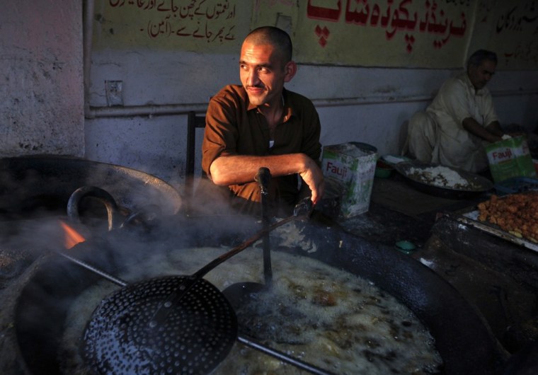 A man pauses while cooking pakoras at a stall in Abbottabad .