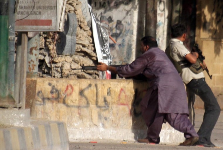 Pakistani security officials in civilian clothing take position following an operation against alleged criminals in restive Lyari area of southern port city of Karachi on April 27, 2012.