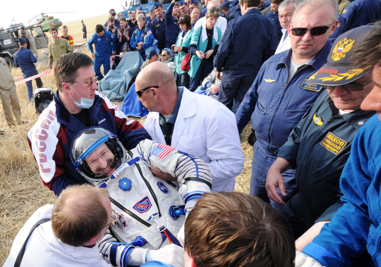 Russia's space agency ground personnel help US astronaut Dan Burbank shortly after the landing of Soyuz TMA-22 capsule near the town of Arkalyk in Kazakhstan, on April 27, 2012. US astronaut Dan Burbank, Russian cosmonauts Anton Shkaplerov and Anatoly Ivanishin, landed today safely in the Kazakh steppe aboard a Russian Soyuz capsule after a stay of over five months aboard the International Space Station.