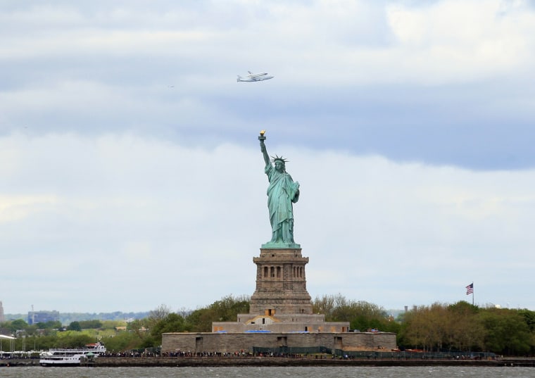 Riding atop a 747 shuttle carrier aircraft, the space shuttle Enterprise flies past the Statue of Liberty in New York Harbor on April 27, in New York City. Enterprise, which was flown from Washington, DC, will eventually be put on permanent display at the Intrepid Sea, Air and Space Museum.