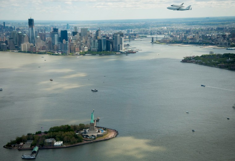 The space shuttle Enterprise, mounted atop a NASA 747 Shuttle Carrier Aircraft, flies near the Statue of Liberty and the Manhattan skyline, April 27, in New York City. Enterprise was the first shuttle orbiter built for NASA performing test flights in the atmosphere and was incapable of spaceflight. Originally housed at the Smithsonian's Steven F. Udvar-Hazy Center, Enterprise will be demated from the SCA and placed on a barge that will eventually be moved by tugboat up the Hudson River to the Intrepid Sea, Air & Space Museum.