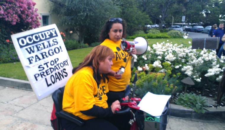 Ana Casas Wilson, sitting, and an unidentified protester demonstrating in front of the home of Wells Fargo CFO Tim Sloand on Thursday.