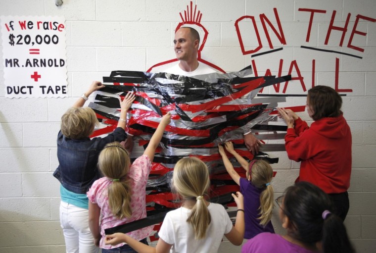Ooltewah Elementary School students duct tape Principal Tom Arnold to a wall in the hallway during their lunch hour on April 27 in Ooltewah, Tenn. Arnold made an agreement with the students that if they reached their walk-a-thon fundraising goal of $20,000, he would spend the lunch hour duct taped to the wall.