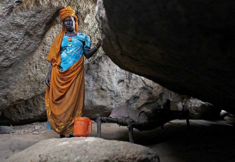 A woman stands in a cave next to her bedridden mother in Bram village in the Nuba Mountains, South Kordofan.