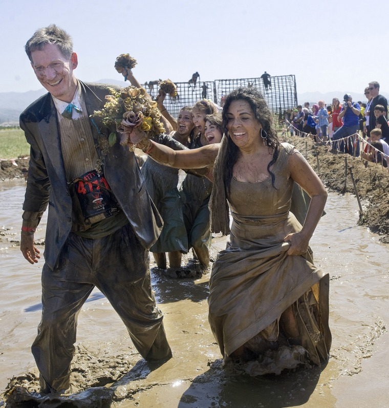 As spectators cheer the bride and groom, Sandra Parker and Andrew Keith, the couple finishes the last muddy leg of the Gladiator Rock N' Run.