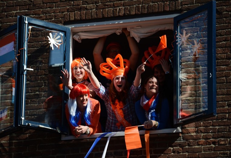 Spectators wave to Queen Beatrix from a window in Rhenen.