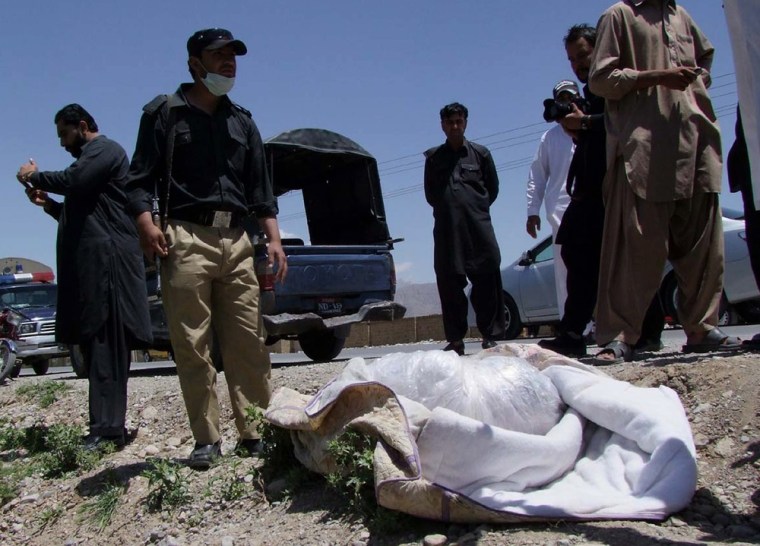 Pakistani security officials stand next to covered body of British Red Cross worker Khalil Rasjed Dale at the site in Quetta, Pakistan on Sunday, April 29, 2012.