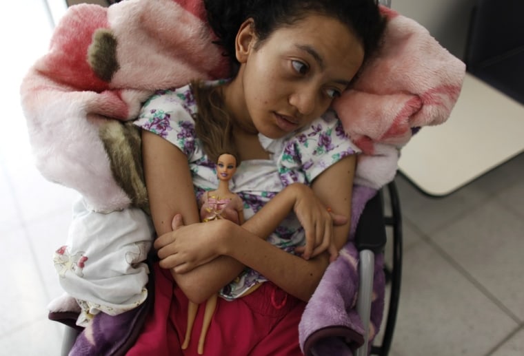 A disabled girl embraces a doll during a session of physical therapy at the AACD on March 19.