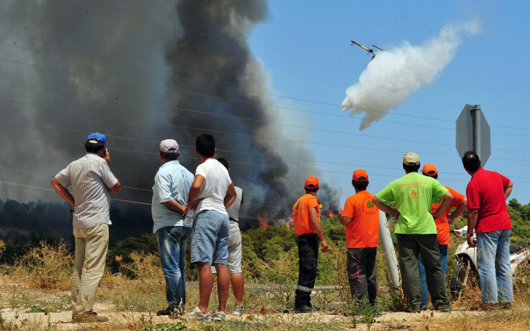 Locals watch a firefighting plane trying to extinguish a wildfire on the mountain of Spathovouni, near Corinth city, Peloponnese, southern Greece, August 8.