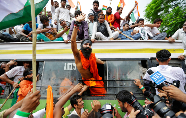 Indian yoga guru Baba Ramdev waves out of the window of a bus after he was detained with his supporters by policemen in New Delhi, India, on Aug. 13. Waving Indian flags and shouting slogans, the protesters climbed into a row of police buses parked around the sprawling New Delhi fairground that Ramdev and his supporters had occupied for the past four days.