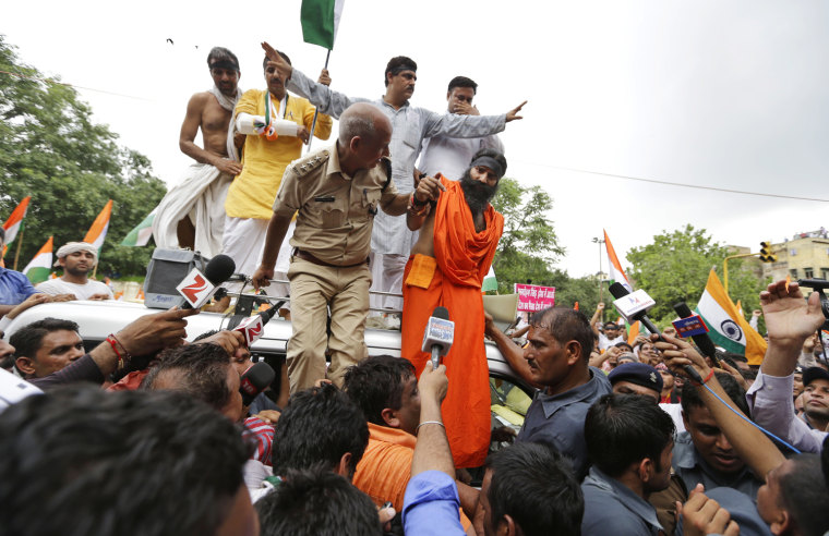 Indian yoga guru Baba Ramdev, right in an orange robe, is detained by police in New Delhi, India, on Aug. 13. Waving Indian flags and shouting slogans, followers of Ramdev climbed into a row of police buses parked around the sprawling New Delhi fairground that Ramdev and his supporters had occupied for the past four days.