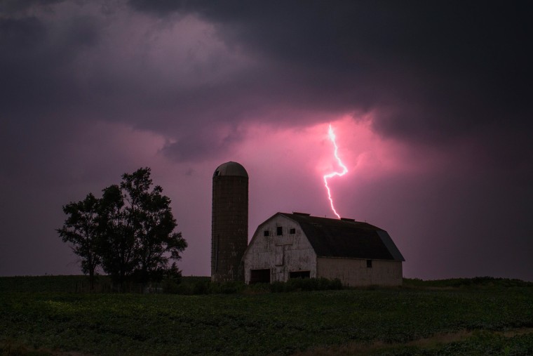 Lightning strikes over a barn surrounded by a soybean crop in Donnellson, Iowa, July 13, 2012.