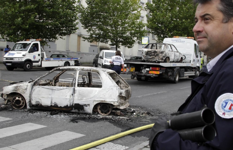 French police stand guard near cars destroyed in overnight clashes where gangs of youths set cars and buildings ablaze in Amiens August. About 100 youths burned cars, a leisure centre and a nursery school according to an official from the prefect's office.