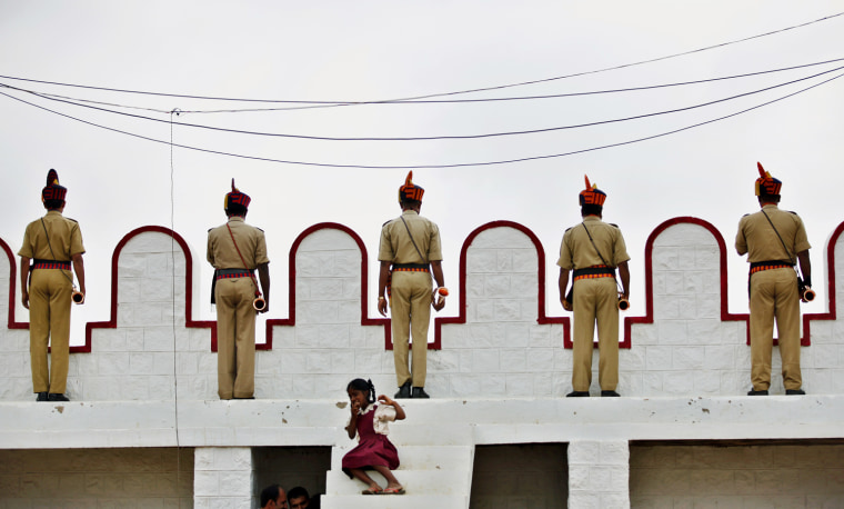 Members of police wait with their trumpets to perform as a school girl sits on steps during a gathering on the occasion of 65th anniversary of India's independence from British rule, in Bangalore, India, on Aug. 15.