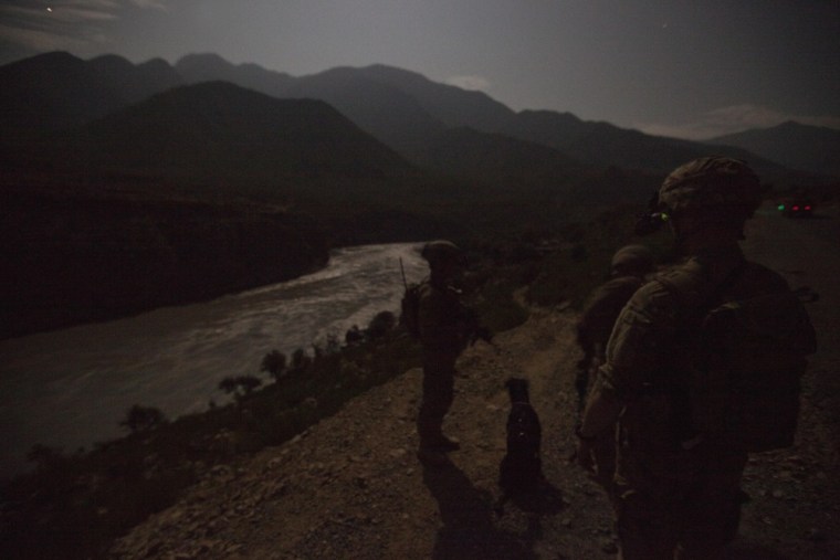Illuminated only by moonlight, Sgt. Jeremy Boetjer, 28, of Fort Wayne, Ind, right, along with Taz, look out across the Kunar river during a night mission on Sept. 13, in Afghanistan.