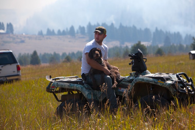 Flynn Harmon of Cle Elum, Wash. sits on his ATV holding Loner, a German Wirehaired Pointer while looking for his other dog, Frida.