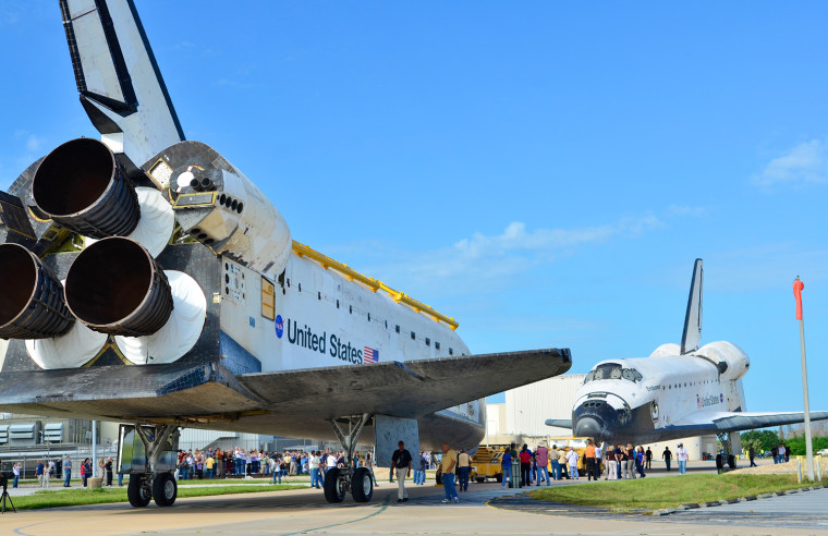 Space Shuttles Atlantis, left, and Endeavour face each other as the Endeavour backs out of the Orbiter Processing Facility and Atlantis is moved out of the Vehicle Assembly Building Aug. 16, in Cape Canaveral, Fla. The Endeavour will be moved to the California Science Center as a permanent exhibit and the Atlantis will be kept at the Kennedy Space Center Visitor Complex.