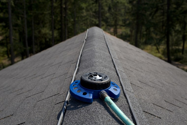As a last-ditch effort, a sprinkler is placed on the roof of one of the cabins at Huntley Lodge in Cle Elum, Wash. The sprinkler is intended to wet the roof as a last line of defense agains the Taylor Bridge Fire.
