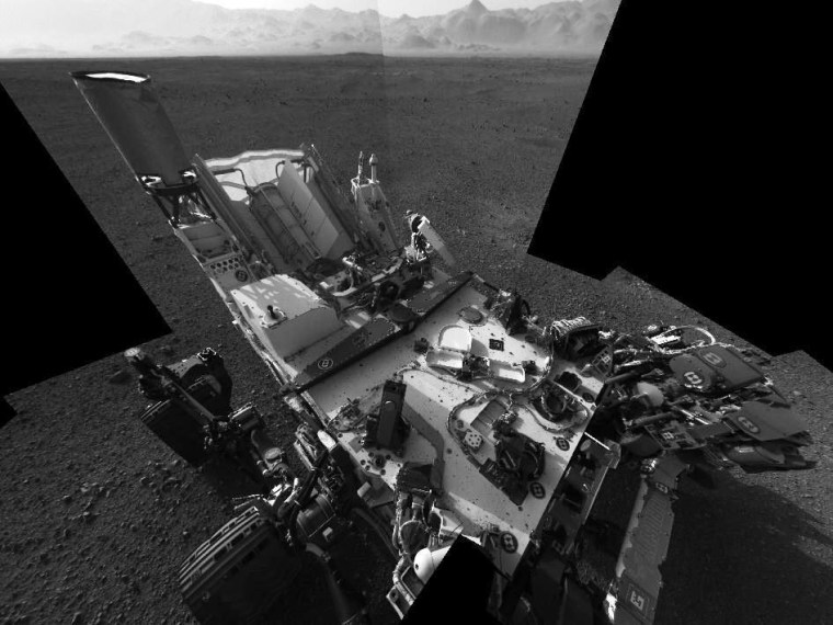 A self-portrait shows the deck of NASA's Curiosity rover, as seen by the rover's navigation camera. The rim of Gale Crater is visible in the far background. This distorted mosaic does not show the camera mast on which the Navcam system is mounted.