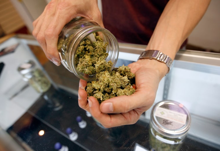 A budtender pours marijuana from a jar at Perennial Holistic Wellness Center medical marijuana dispensary in Los Angeles on July 25.