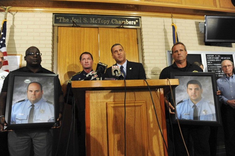 St. John the Baptist Parish Sheriff Mike Tregre (center), with Louisiana State Police Colonel Mike Edlmonson, (left), speaks at a press conference with two officers holding portraits of Brandon Nielsen (left) and Jeremy Triche, after an early morning shooting that left the two police officers dead and two other police officers injured in LaPlace, Louisiana.