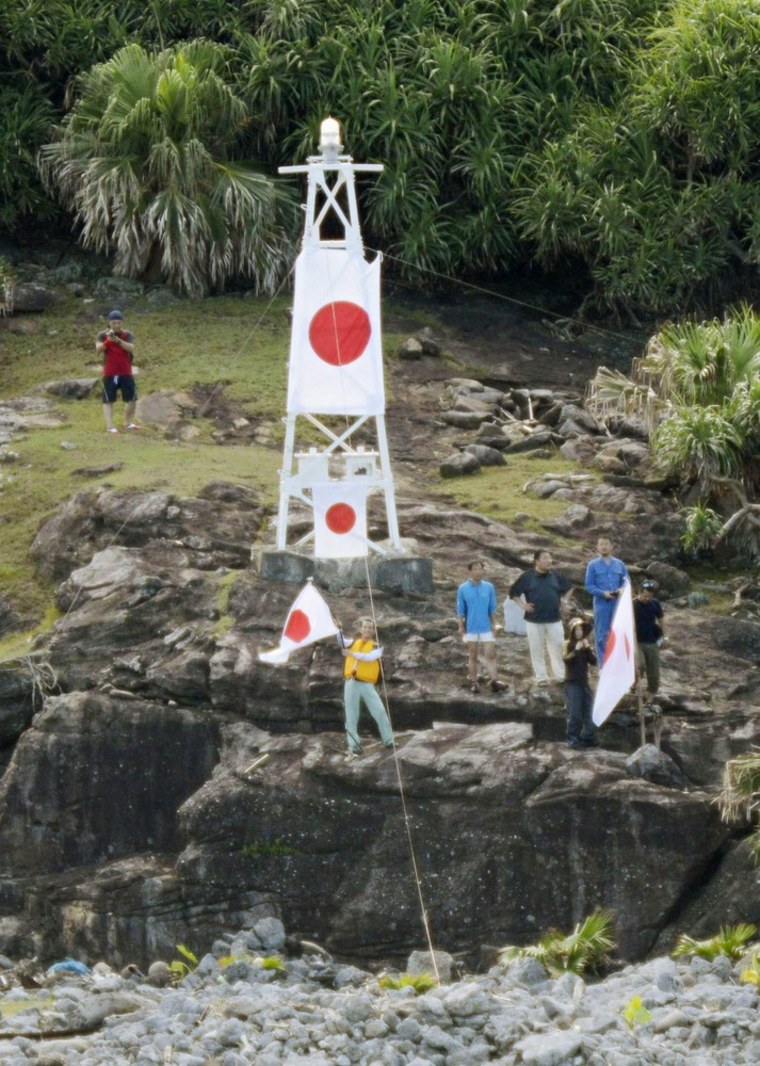 Members of a Japanese nationalist group raise Japanese flags as they land on Uotsuri island, part of the disputed islands in the East China Sea, known as the Senkaku isles in Japan, Diaoyu islands in China, on Sunday.