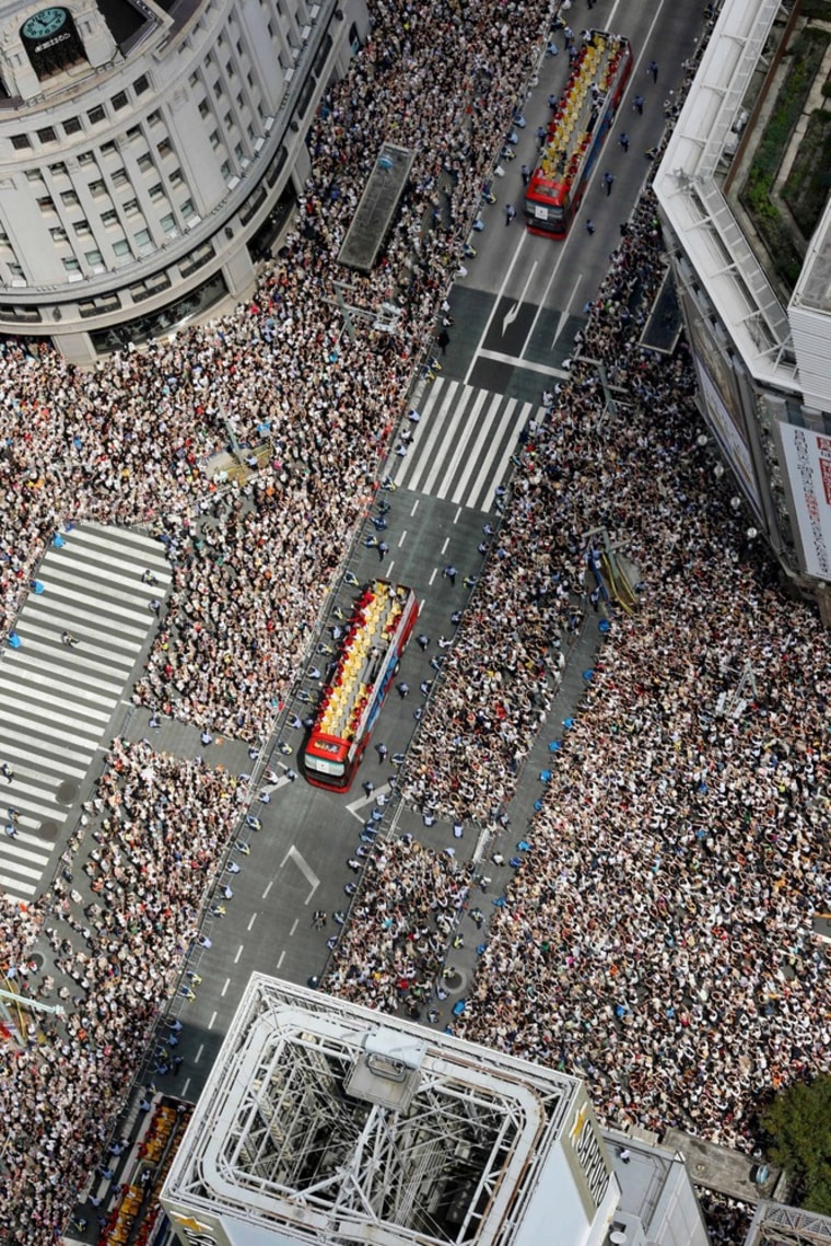 People pack the central intersection of Tokyo's Ginza shopping district as Japanese Olympic medalists and athletes who competed in the London Games aboard double-decker buses parade through the main street Monday, Aug. 20.
