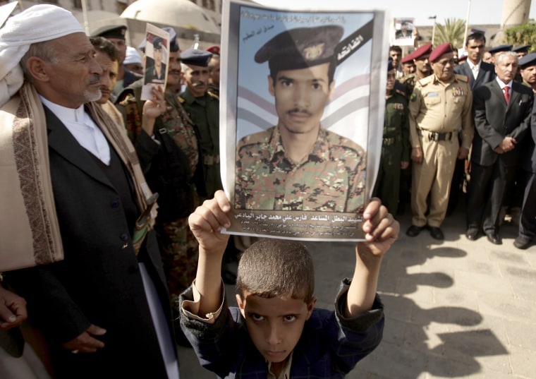 A Yemeni boy holds a poster of his father, who was killed in an attack in the city of Aden, during his funeral in Sanaa, Yemen, on Aug. 20, 2012.