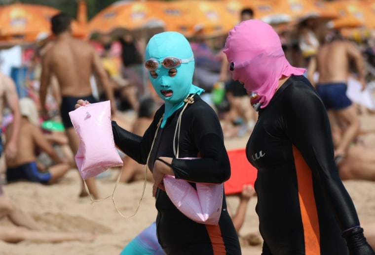 Chinese beachgoers wear body suits and protective head masks, dubbed