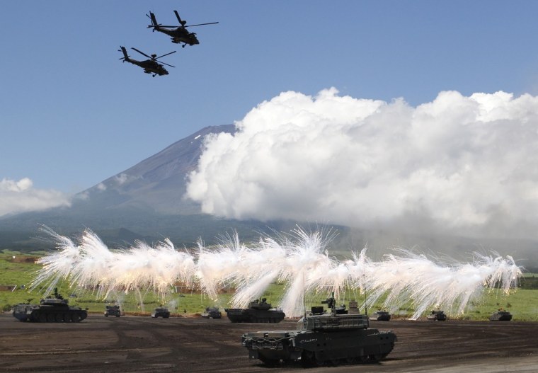 A line of Japan Ground Self-Defense Force tanks flare up a smoke screen during the annual live-firing exercise and demonstration at Higashi Fuji training range in Gotemba, southwest of Tokyo, on August 21, 2012.