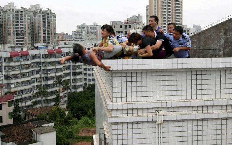Rescuers and relatives stop a woman from committing suicide by jumping off a building in Zhanjiang, Guangdong province August 14, 2012.