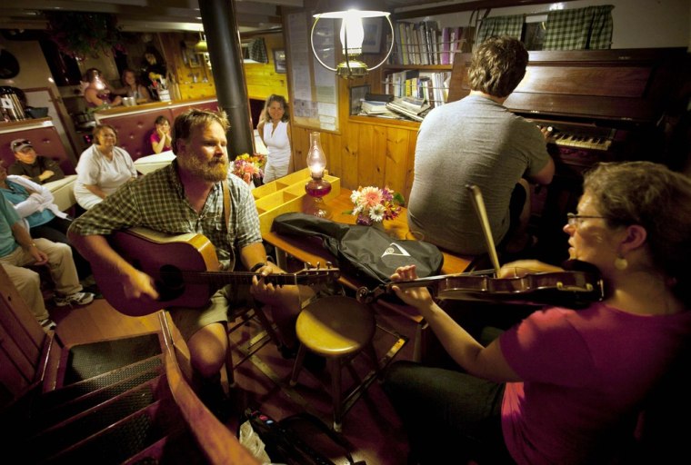 Captain Barry King, on the guitar, joins passengers Sarah Washburn, playing violin, and her husband, Ryan Jesperson, during a musical evening aboard the Mary Day off Ilseboro, Maine.