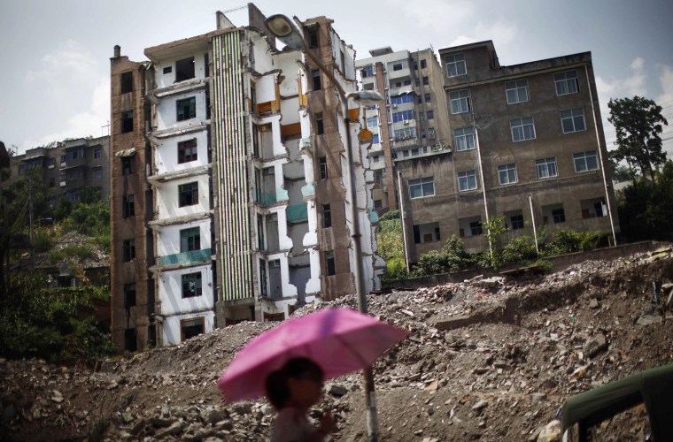 A woman walks past a building under demolition at a residential area to be relocated, Huangtupo, Badong city, 62 miles from the Three Gorges dam, in Hubei province, China, Aug. 8.