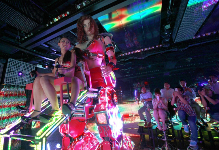Bikini-clad women operate a 3.6 meter-high custom-made female robot as customers take photos, at the newly opened