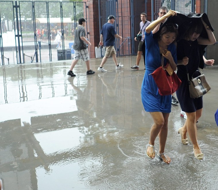 Fans seek shelter from heavy rain after play was suspended on the first day of the 2012 US Open Tennis Championship.
