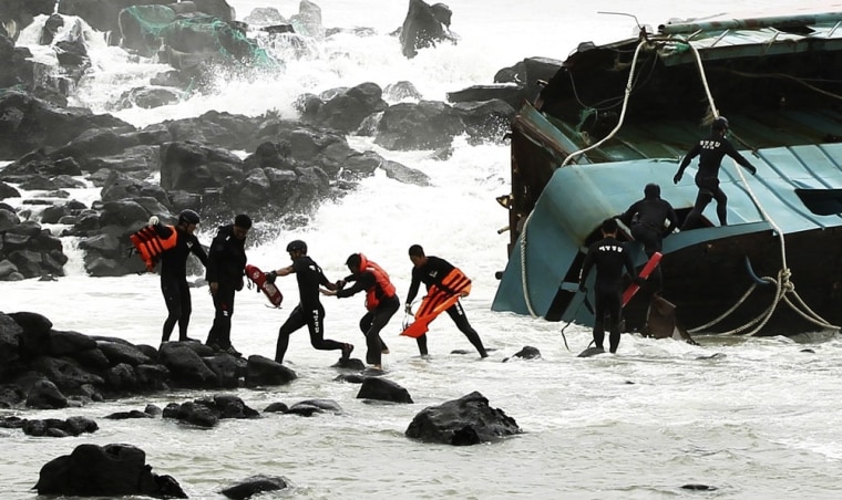 A Chinese fisherman wearing an orange life vest, fourth from left, is rescued by South Korean coast guard officers from a Chinese ship in Jeju, South Korea, on August 28, 2012. A powerful typhoon pounded South Korea with strong winds and heavy rain Tuesday, while the nation's coast guard battled rough seas in a race to rescue fishermen on two Chinese ships that slammed into rocks off the southern coast.