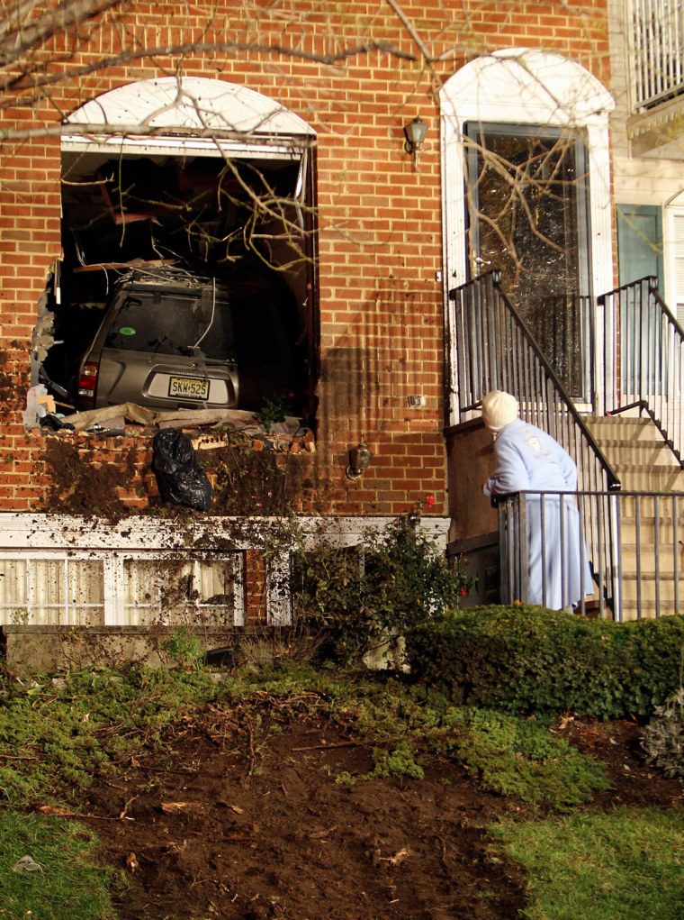 A neighbor takes a peek at a Nissan Pathfinder which crashed and landed in the house belonging to Gloria Sinclair, 74, late on Dec. 8, 2011, near the intersection of West Market Street and Wickliffe Street in Newark. No one was injured, but Ms. Sinclair was home at the time with her daughter and 2 year-old grandson. A few short minutes before the accident, her grandson had left that room, a computer room, which the SUV crashed into.