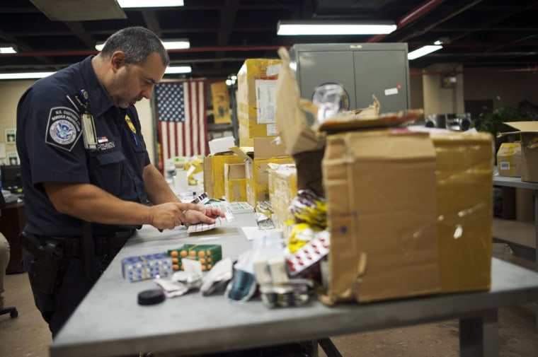 U.S. Customs and Border Protection officer Boris Sapozhnikov looks at counterfeit drugs seized by the agency on Aug. 15 at its offices at John F. Kennedy Airport in New York.