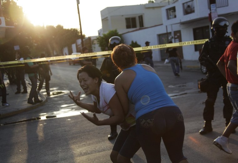 A woman is held back by another woman as she reacts to the killing of several people at a crime scene in Monterrey, Mexico on August 29, 2012.