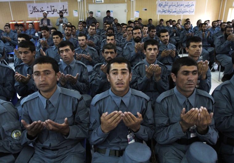 Afghan national police officers pray during their graduation ceremony.