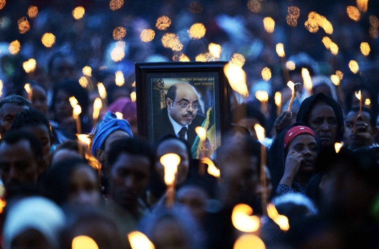Mourners hold up a picture of deceased Prime Minister Meles Zenawi during a candle lit vigil in Meskel square, in Addis Ababa on August 30.