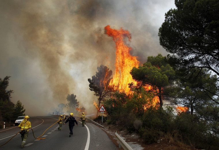 Firefighters work to control a raging forest fire as trees are engulfed in flames next to a road in Ojen, southern Spain, on Aug. 31.