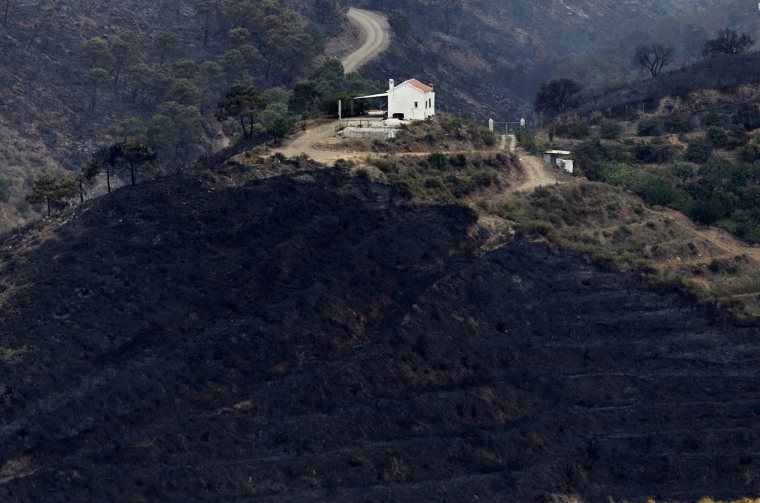 Burnt out land is seen around a house atop a hill after a forest fire in Ojen, southern Spain, on Aug. 31.