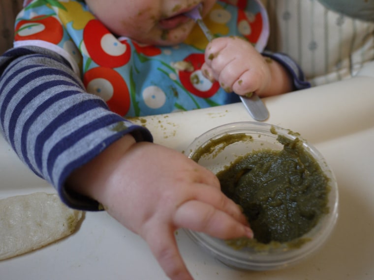 The writer's son enjoying (or at least playing with) homemade spinach-and-potato puree.