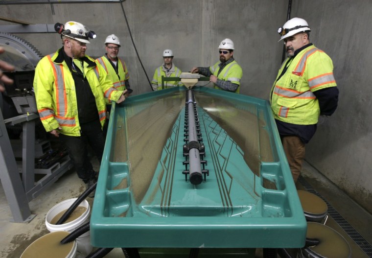 Matt Collins, chief operating officer of the Sutter Gold Mining Co., left, watches as, from left, Allen Smith, Brain Herfel, Ted Chapman and Wayne Murphy calibrate the water flow of a gravity table at the company's newly constructed mill near Sutter Creek, Calif. The gravity table uses technology similar to those used by gold rush-era miners who used pans to separate gold from surrounding materials.