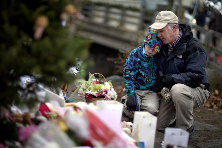David Freedman, right, kneels with his son Zachary, 9, both of Newtown, Conn., as they visit a sidewalk memorial for the Sandy Hook Elementary School shooting victims on Dec. 16.